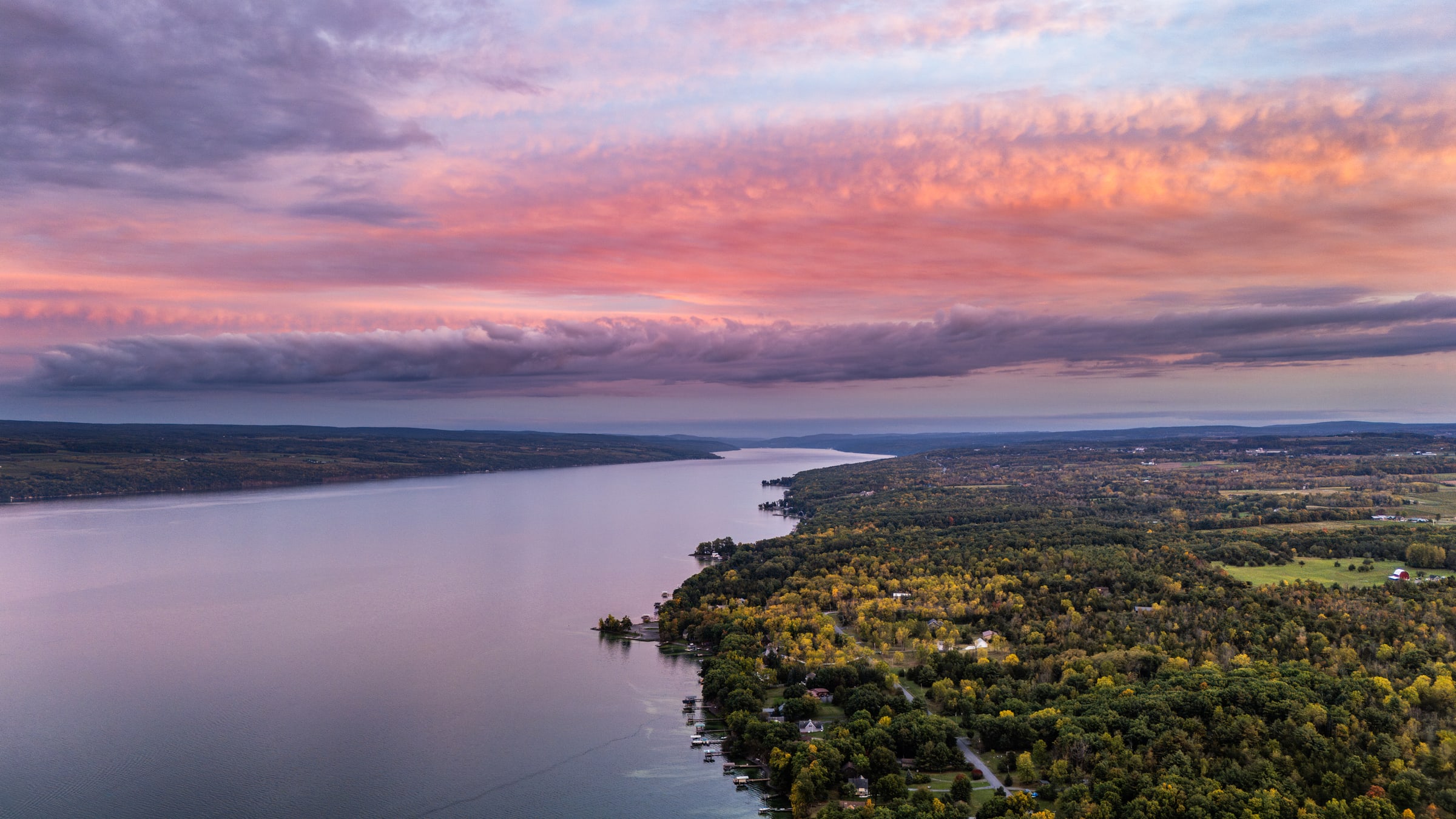 Aerial twilight view of downtown Penn Yan with colorful sunset clouds and Keuka Lake in the distance.